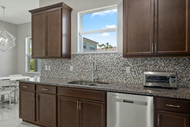 kitchen with dark stone countertops, dishwasher, hanging light fixtures, and sink