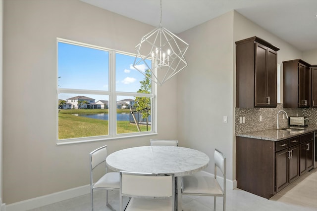 dining room with sink, a water view, and a chandelier