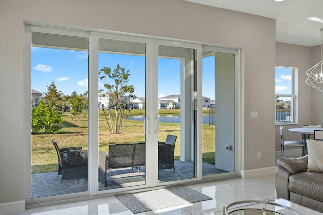 doorway with a chandelier, light tile patterned floors, a water view, and plenty of natural light