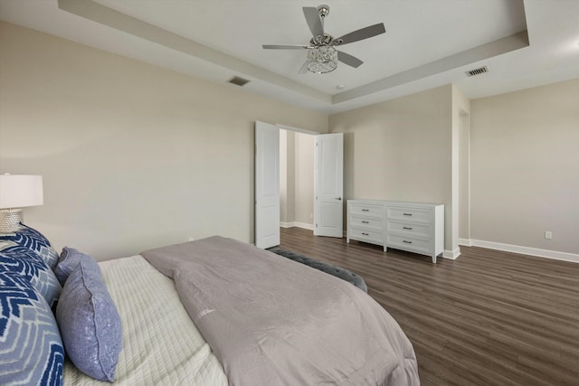 bedroom with dark hardwood / wood-style floors, a raised ceiling, and ceiling fan