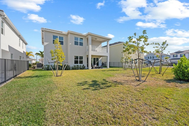 rear view of house featuring central AC unit, a balcony, and a yard