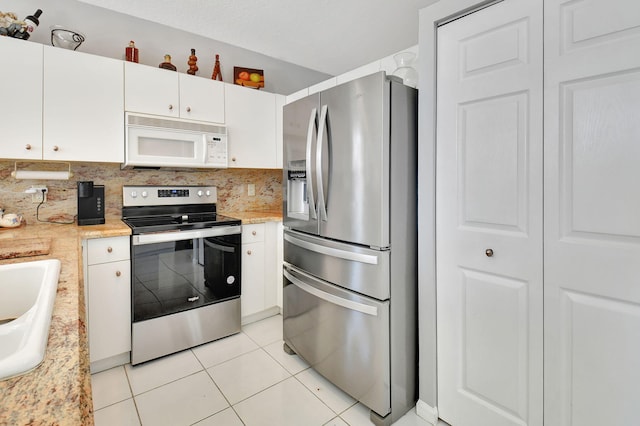 kitchen with sink, light tile patterned floors, tasteful backsplash, white cabinets, and appliances with stainless steel finishes