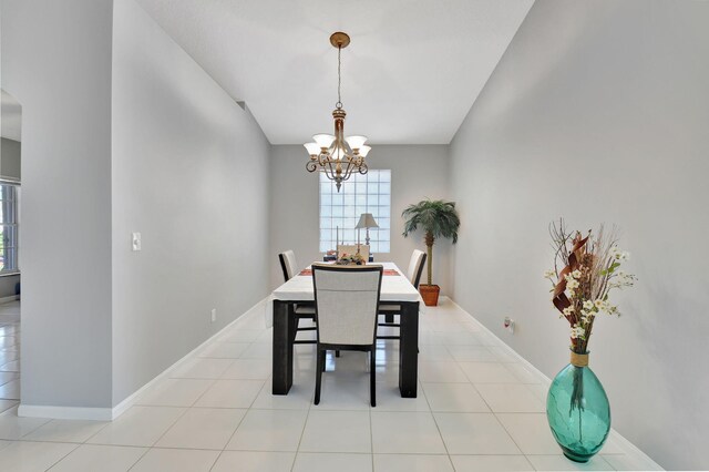 tiled dining area featuring an inviting chandelier and lofted ceiling