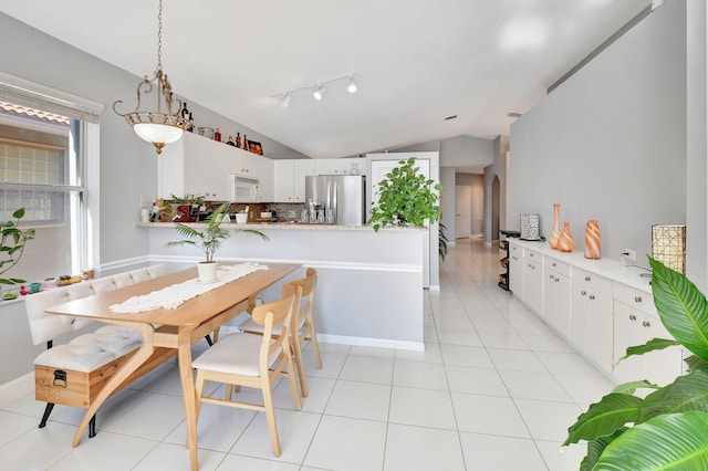 dining space with light tile patterned flooring and lofted ceiling