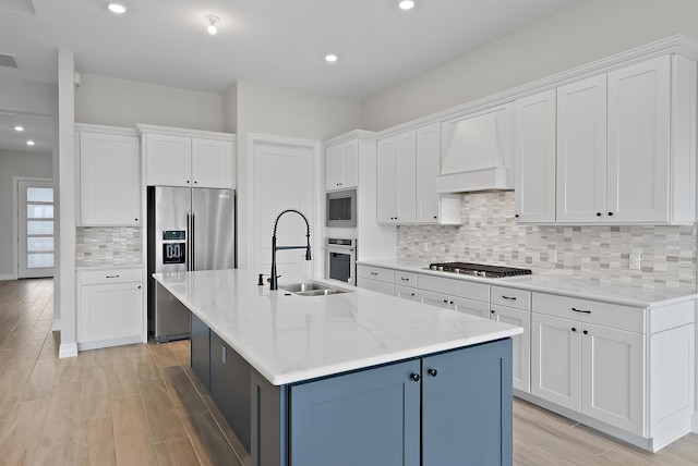 kitchen with white cabinets, sink, stainless steel appliances, and a kitchen island with sink