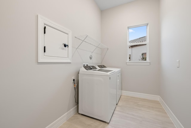 laundry room with separate washer and dryer and light hardwood / wood-style flooring