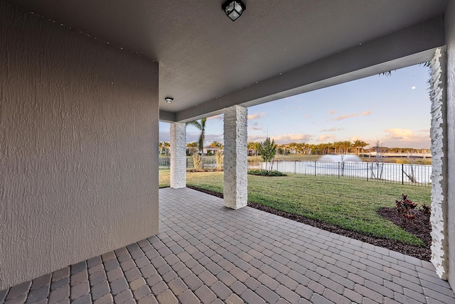 patio terrace at dusk featuring a yard and a water view