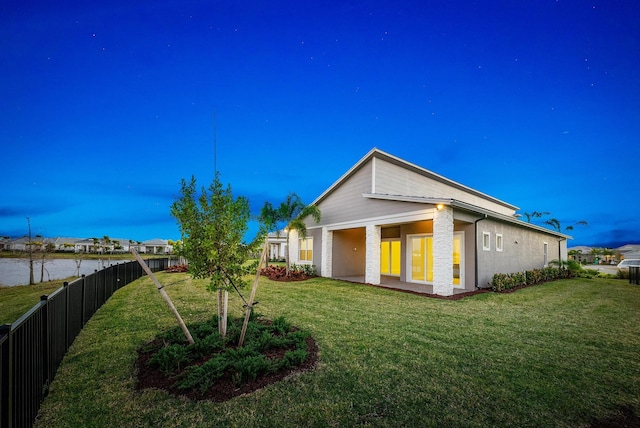 back of house with a lawn and a water view