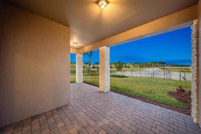 patio terrace at dusk with a lawn and a water view