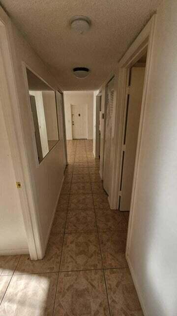 hall with tile patterned flooring and a textured ceiling