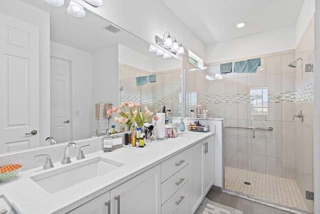 bathroom with hardwood / wood-style floors, vanity, and a shower with shower door