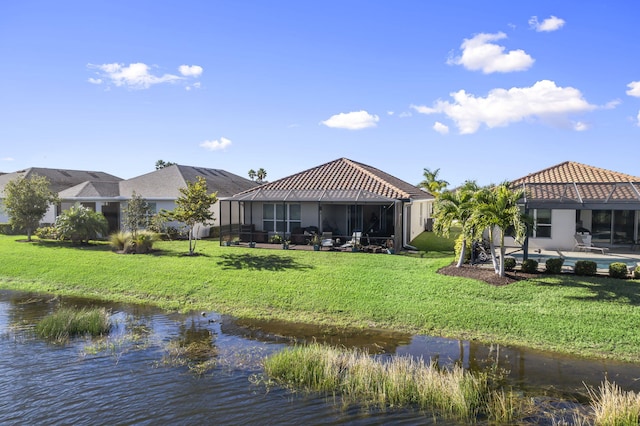 back of property with a water view, a yard, and a swimming pool