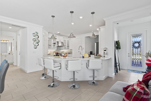 kitchen with a kitchen breakfast bar, kitchen peninsula, pendant lighting, white cabinets, and ornamental molding