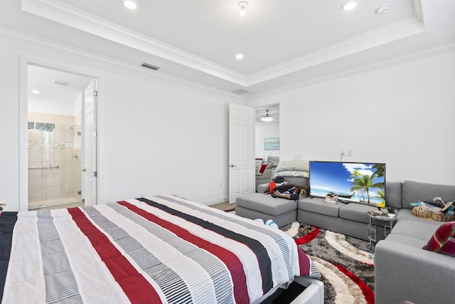 bedroom featuring ornamental molding, a tray ceiling, and ensuite bath