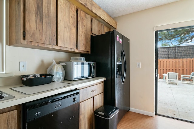 kitchen featuring light hardwood / wood-style flooring, black appliances, and a textured ceiling