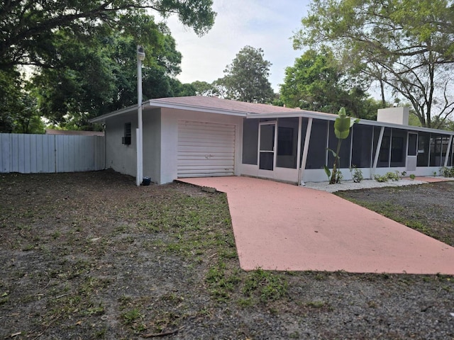 rear view of property featuring a sunroom and a garage