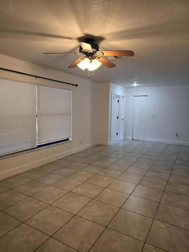 tiled spare room featuring a textured ceiling and ceiling fan