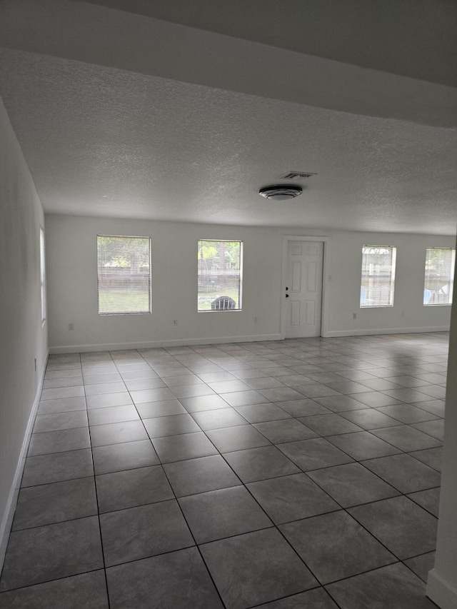 tiled spare room featuring a textured ceiling