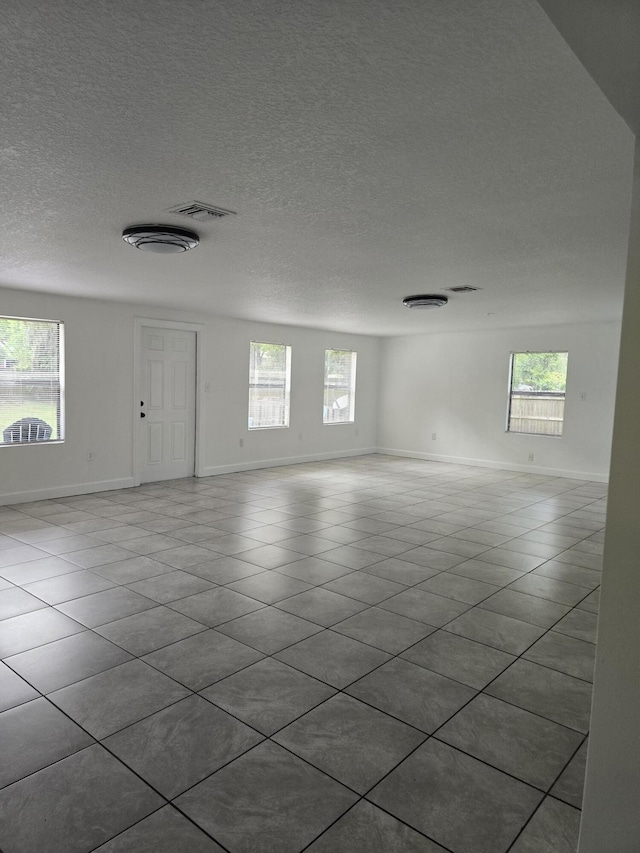 unfurnished room with a wealth of natural light, light tile patterned floors, and a textured ceiling