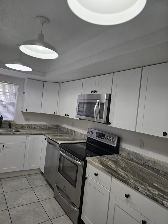 kitchen with white cabinets, decorative light fixtures, sink, and stainless steel appliances