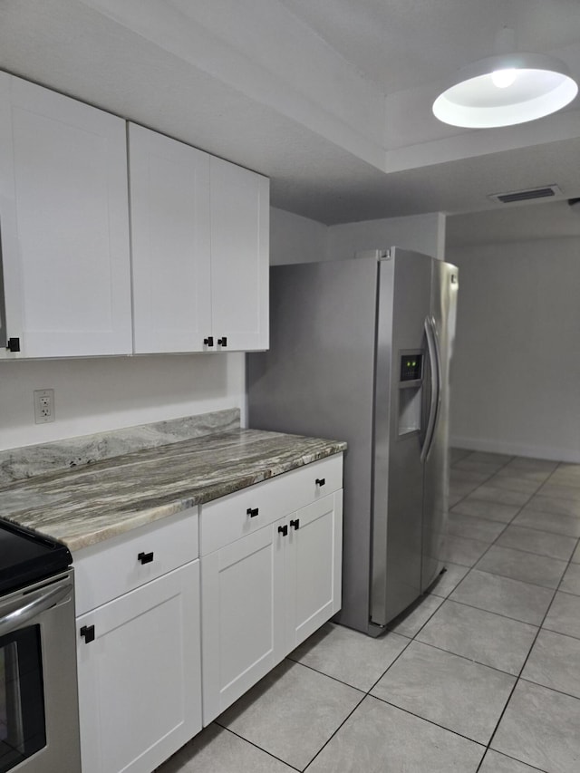 kitchen with white cabinets, light tile patterned floors, stainless steel appliances, and light stone countertops