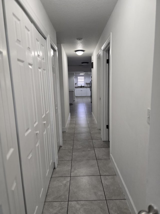 hall featuring tile patterned flooring and a textured ceiling