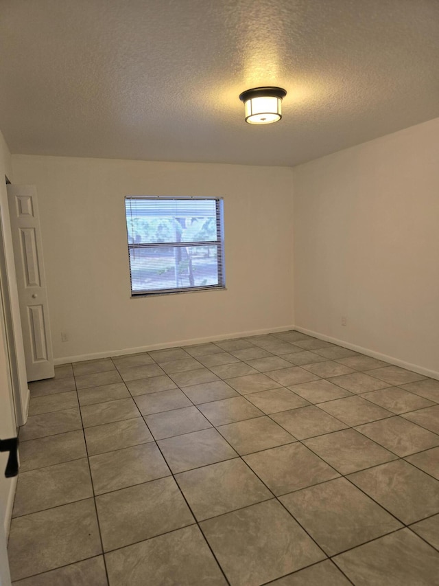 tiled empty room featuring a textured ceiling