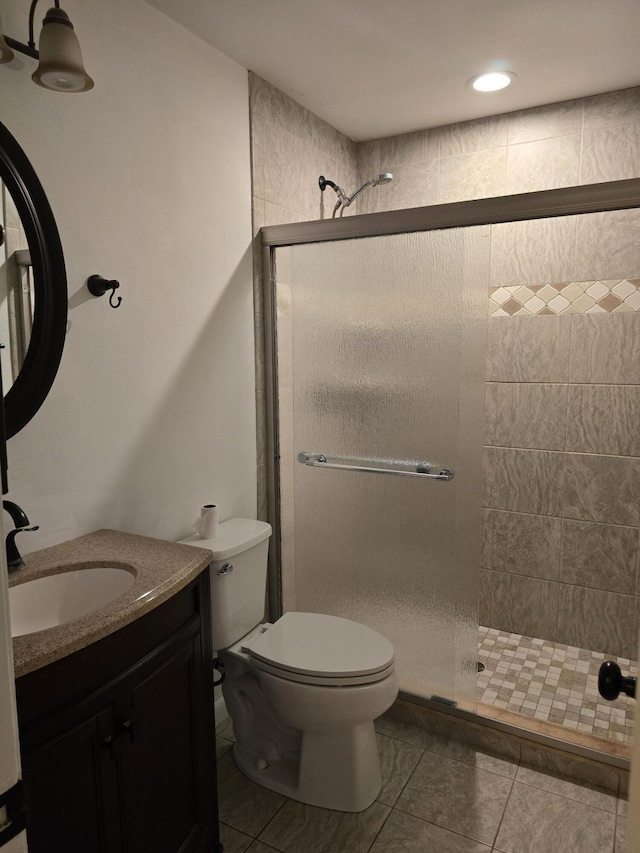 bathroom with tile patterned floors, vanity, toilet, and an enclosed shower