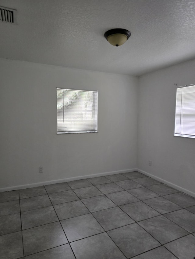 spare room featuring tile patterned floors and a textured ceiling