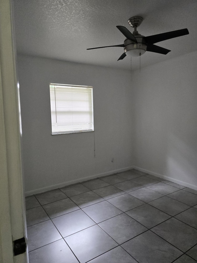 tiled empty room featuring ceiling fan and a textured ceiling