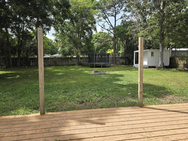 wooden deck with a lawn and a trampoline