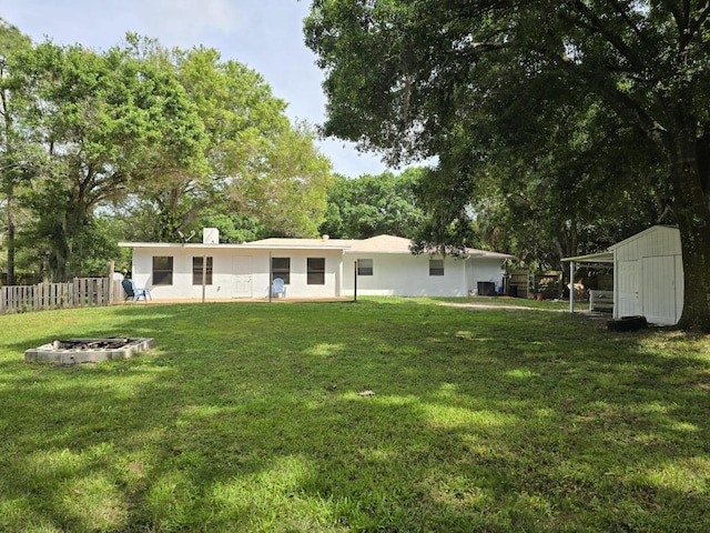 back of house with a yard and a storage unit