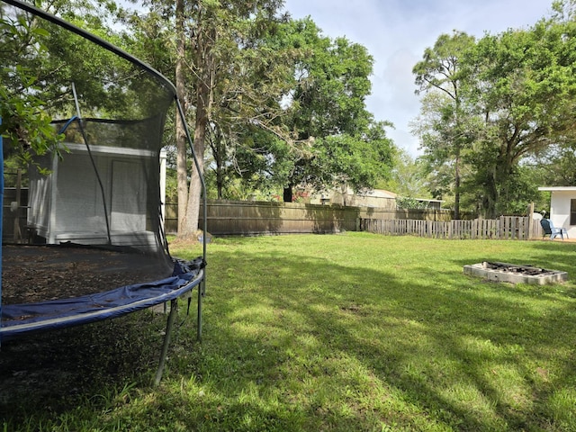 view of yard with a trampoline and an outdoor fire pit