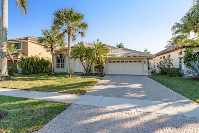 mediterranean / spanish-style home featuring a front lawn and a garage