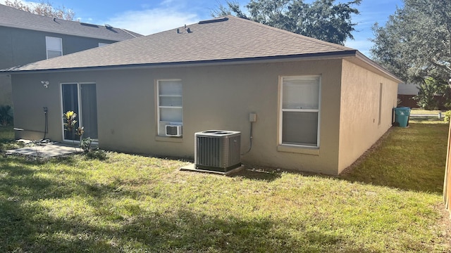 rear view of house with cooling unit, a yard, and central air condition unit