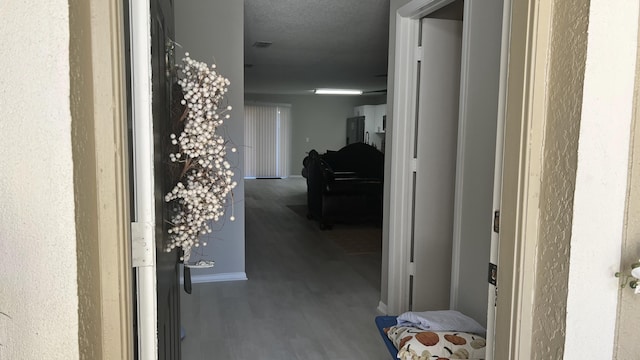 hallway with hardwood / wood-style floors and a textured ceiling