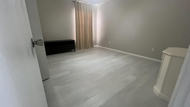 unfurnished room featuring a chandelier and light wood-type flooring