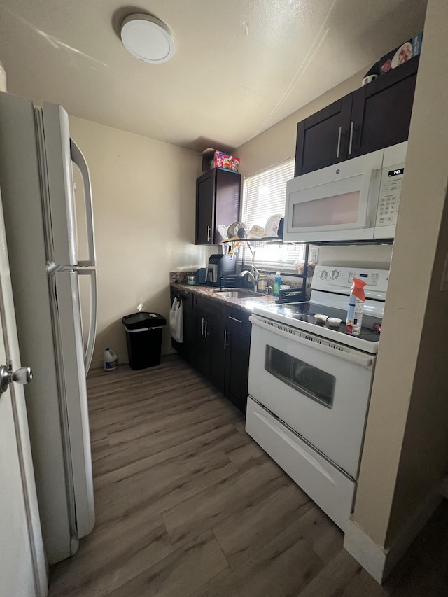 kitchen with dark hardwood / wood-style flooring, white appliances, and sink