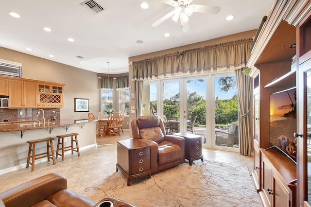 tiled living room with ceiling fan and french doors