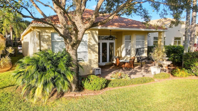 rear view of property with ceiling fan, a patio area, and a lawn