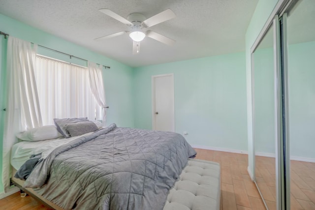 bedroom featuring ceiling fan, a closet, light hardwood / wood-style floors, and a textured ceiling