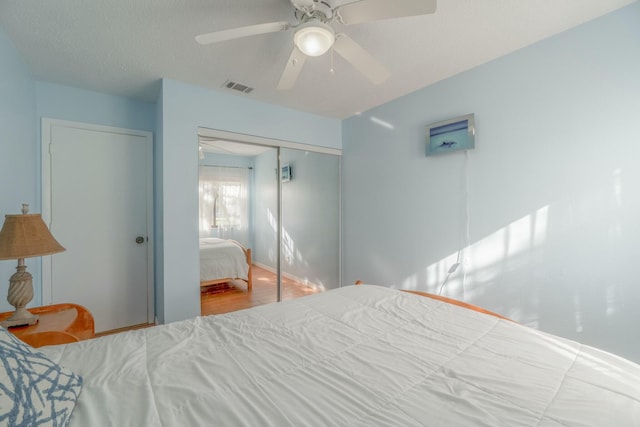 bedroom with ceiling fan, light hardwood / wood-style floors, and a closet