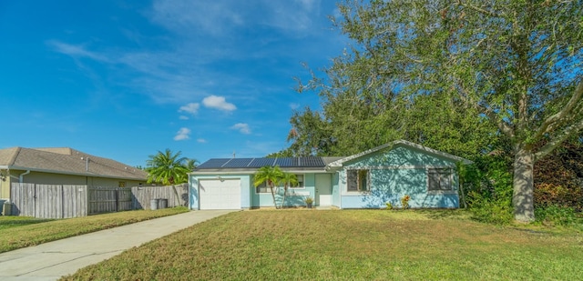 single story home with a garage, a front yard, and solar panels