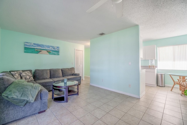 living room with ceiling fan, light tile patterned floors, and a textured ceiling