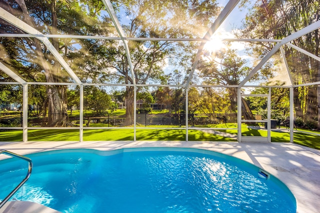 view of swimming pool with a lawn and a lanai