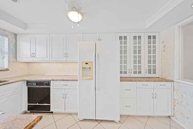 kitchen with white refrigerator with ice dispenser, light tile patterned floors, white cabinets, and a raised ceiling