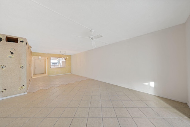 tiled spare room featuring ceiling fan with notable chandelier