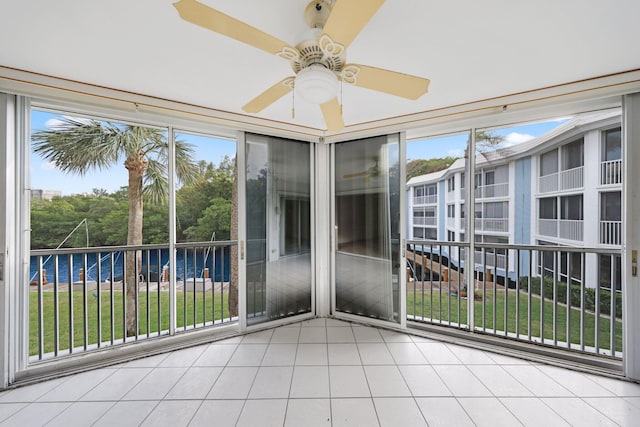 unfurnished sunroom featuring a wealth of natural light, ceiling fan, and a water view