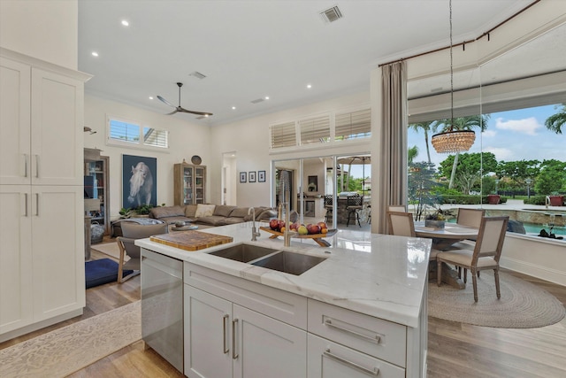 kitchen with dishwasher, light wood-type flooring, white cabinetry, and decorative light fixtures