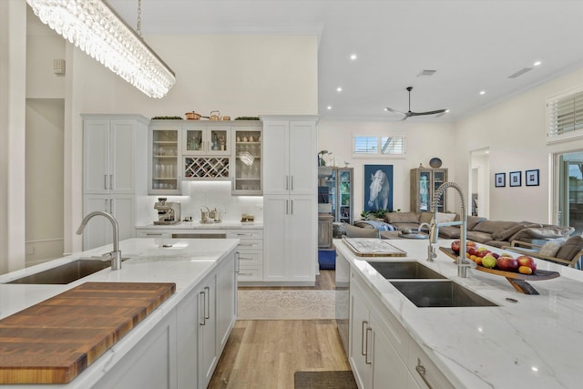 kitchen featuring light hardwood / wood-style flooring, decorative light fixtures, white cabinetry, and sink